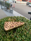 Gold heart-shaped box filled with nuts on a bush with a street and cars in the background