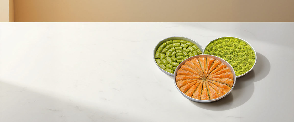 Koçak carrot slice, pistachio rolls and Bülbül Yuvası baklava trays on a marble counter